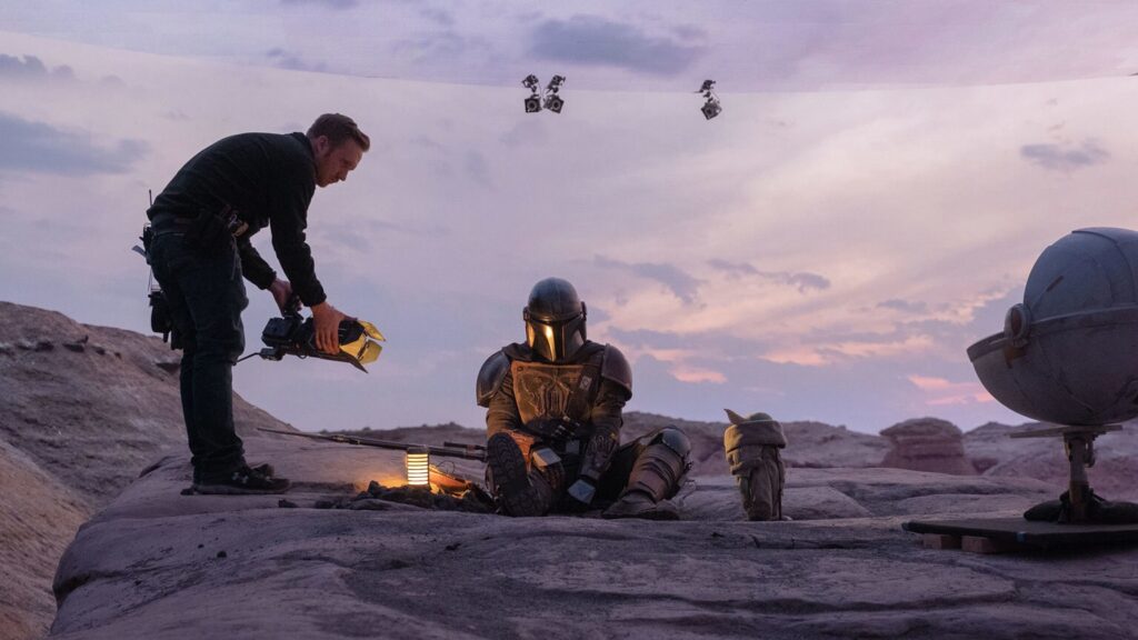 tour du plateau] alt : Le mur d'écrans LED semi-circulaire du tournage de The Mandalorian affichant un désert autour des acteurs